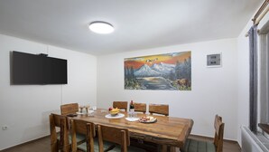 A dining area with a wooden table, chairs, and a painting on the wall.