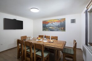 A dining area with a wooden table, chairs, and a painting on the wall. - Villa Velebita in Lika region (Vrhovine)