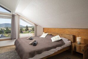 Un dormitorio con un amplio ventanal, cabecera de madera y vistas al campo.