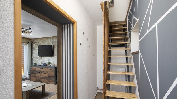 A modern interior with a staircase, a kitchen area, and a dining space.