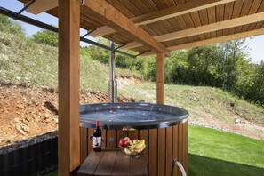 A hot tub under a wooden pergola with a bottle and a bowl of fruit beside it. - Villa Velebita in Lika region (Vrhovine)