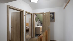A hallway with wooden doors, a bed, a mirror, and a framed painting.