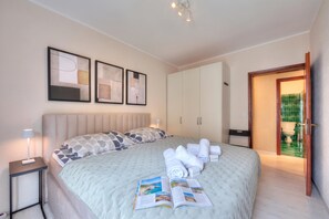 A hotel room with a bed, bedside table, and a door leading to a bathroom. - Emotion Lake Lugano With Direct Lake Access and Shared Pool (Mendrisio)