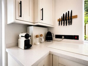 A kitchen with white cabinets, a coffee maker, a kettle, and a knife rack. - Spacious 1BDR bungalow in Leigh on Sea (Southend-on-Sea)