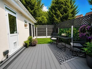 A deck with a black and white patterned rug, a table, and two chairs. - Spacious 1BDR bungalow in Leigh on Sea (Southend-on-Sea)