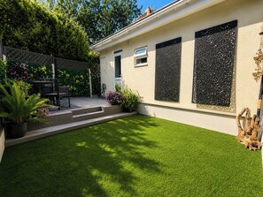Una propiedad residencial con un césped bien cuidado, un patio con mobiliario exterior y plantas decorativas.