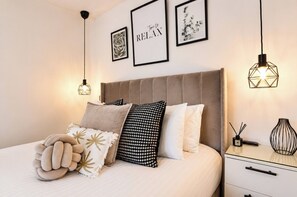 A neatly made bed with multiple pillows and a decorative pillow on a white mattress.