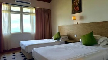 Habitación de hotel con dos camas, una ventana con cortinas, una lámpara de pared y un cuadro enmarcado.