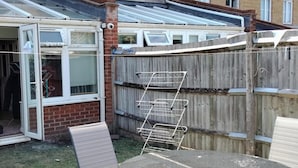 A residential property with a partially open door, a wooden fence, and a metal ladder leaning against it.