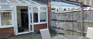 A residential property with a partially open door, a wooden fence, and a metal ladder leaning against it.