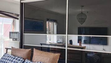 A room with a bed, a desk, a television, and a window with blinds.