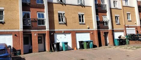 A row of townhouses with brick facades, white garage doors, and balconies with black railings.