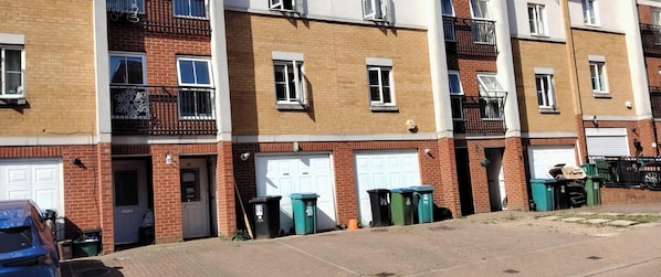 A row of townhouses with brick facades, white garage doors, and balconies with black railings.