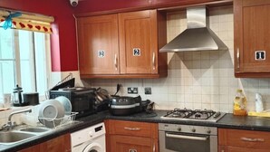 A kitchen with wooden cabinets, a gas stove, a microwave, and a dish rack.