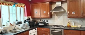 A kitchen with wooden cabinets, a gas stove, a microwave, and a dish rack.