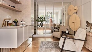 A modern kitchen with a bar area, a seating area with a sofa and armchairs, and a large window providing natural light. - The Secret Escape - Close to the Beach (Sopot)