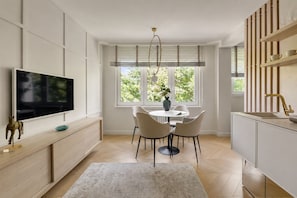 A modern kitchen with a dining area, a TV mounted on the wall, and a window with blinds. - The Secret Escape - Close to the Beach (Sopot)