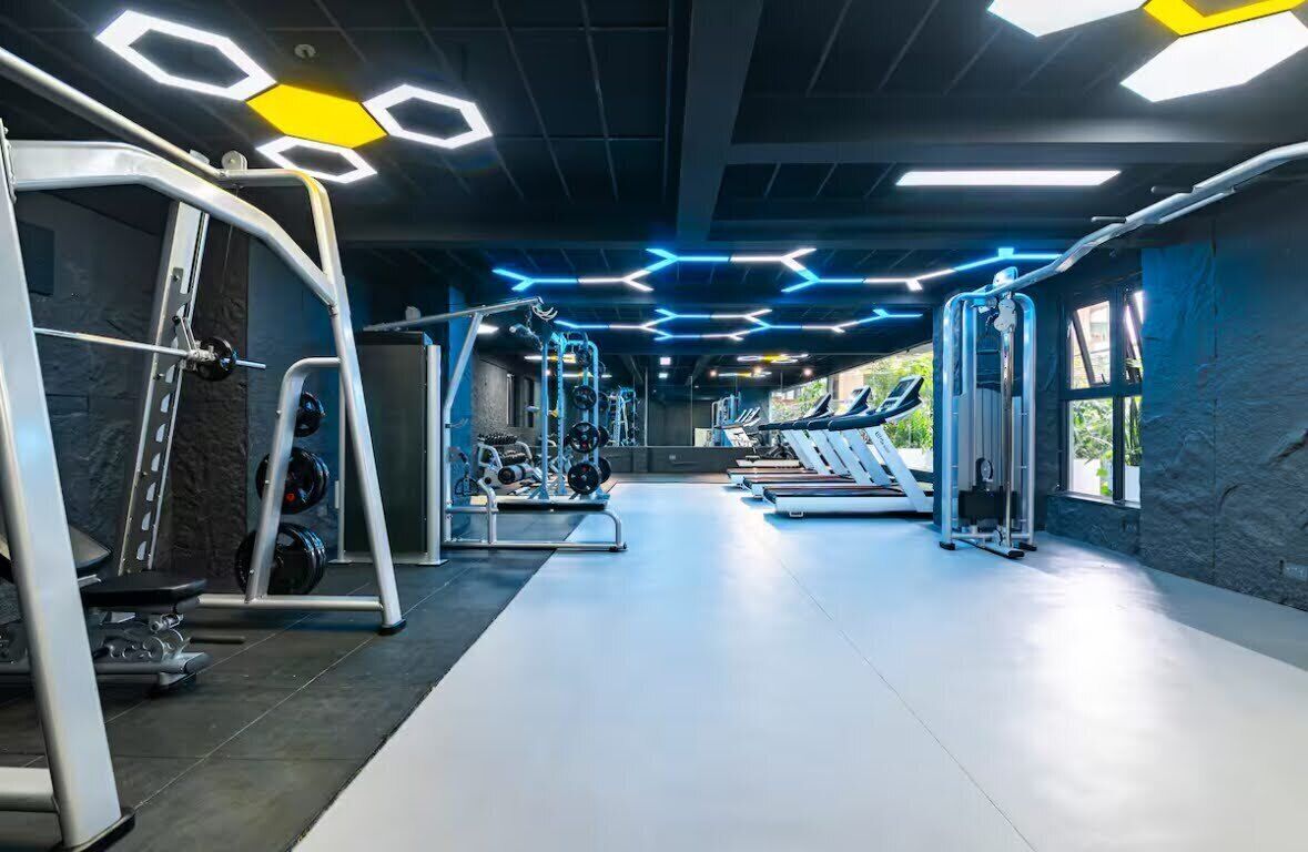 Une salle de sport équipée de divers appareils d’exercice, notamment des tapis de course et des appareils de musculation, et dotée d’un chemin central pour la marche.
