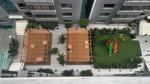 A high-rise building with multiple balconies, a rooftop garden with a swing set, and a sports court. - Takdiri Homes Neptune (Nairobi)