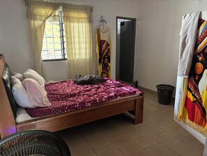 A room with a bed, a window with curtains, a wardrobe, and a door. - Single-story house with an inner courtyard, ideal for a family (Abidjan)