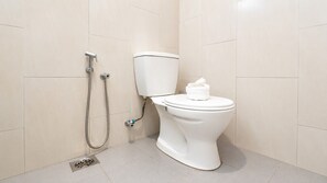 A bathroom with a toilet, a shower, and a towel on the toilet seat. - Swing & Pillows Setapak Central (Kuala Lumpur)