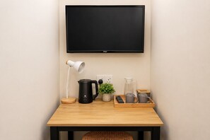 A room with a flat-screen TV mounted on the wall, a desk with a kettle, a coffee maker, a remote control, and a tray with mugs. - Swing & Pillows Setapak Central (Kuala Lumpur)