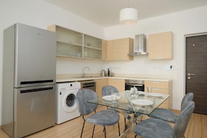 A modern kitchen with a stainless steel refrigerator, a washing machine, and a glass dining table with chairs. - Executive Penthouse w/Balcony Central Nicosia (Nicosia)