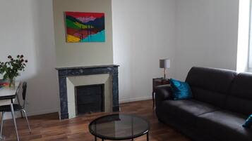 A living room with a fireplace, a sofa, a coffee table, and a painting on the wall.