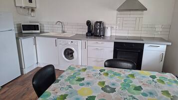 A compact kitchen with a washing machine, a microwave, and a coffee maker.