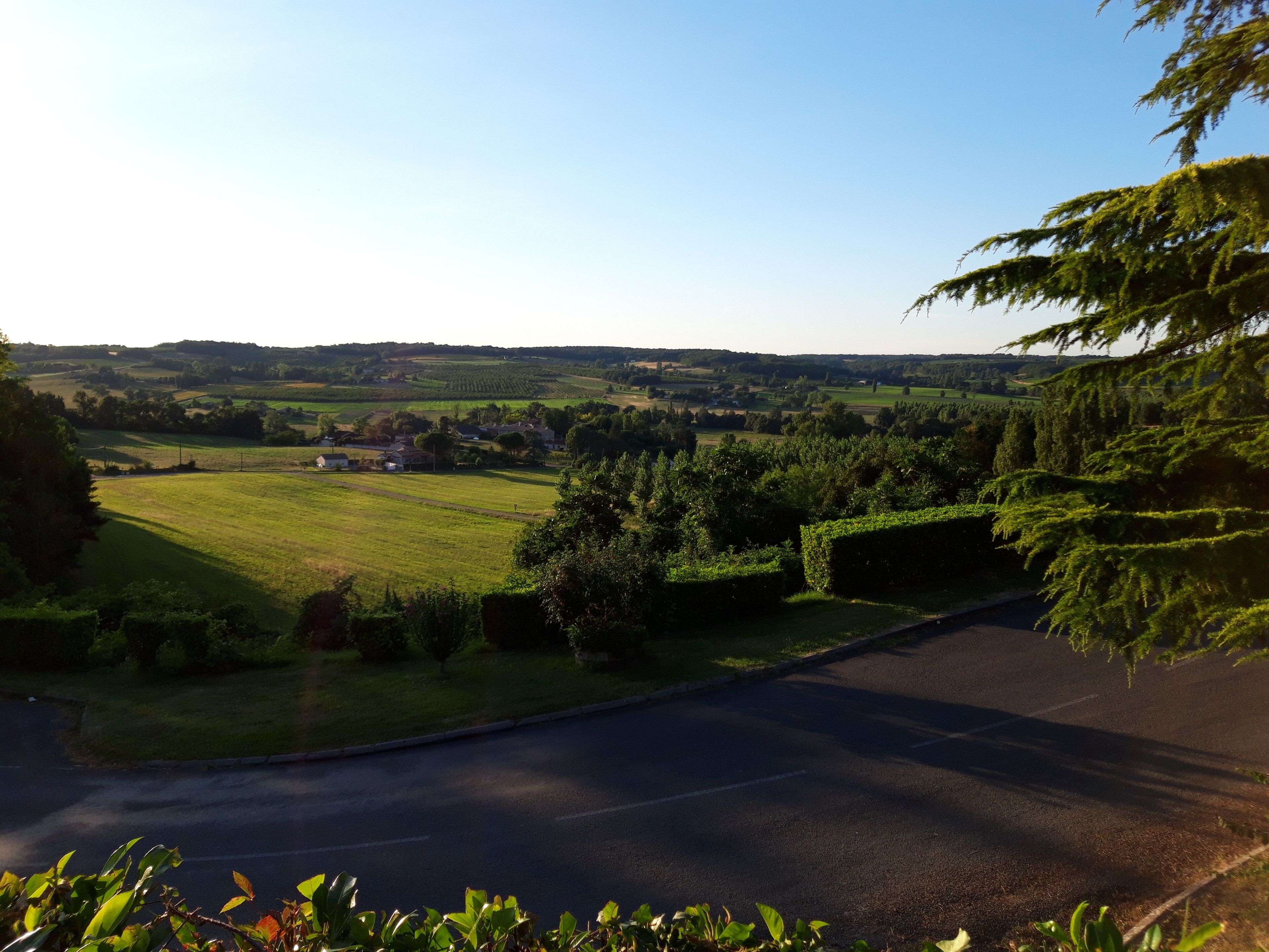 A rural landscape with a road, fields, and a small settlement in the distance.
