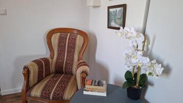 A room with a striped armchair, a small table with books, and a potted orchid.