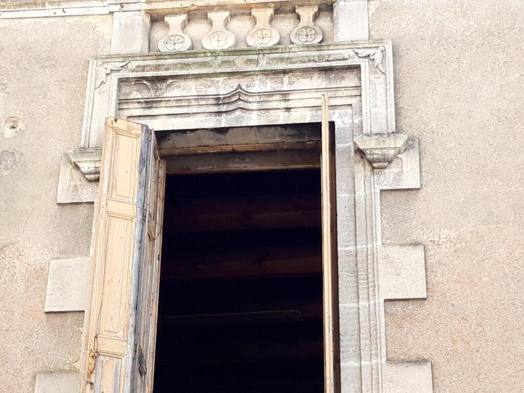 Une porte d’entrée ornée d’un linteau décoratif et d’un battant en bois entrouvert.