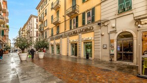 A street with buildings, a wet cobblestone pavement, and a person walking. - [CasadiCavour]5Terre/reach everything by foot +A/C (La Spezia)
