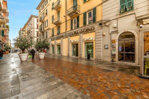 A street with buildings, a wet cobblestone pavement, and a person walking. - [CasadiCavour]5Terre/reach everything by foot +A/C (La Spezia)