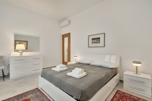 Un dormitorio moderno con una cama grande, mesitas de noche, un aparador y un espejo.