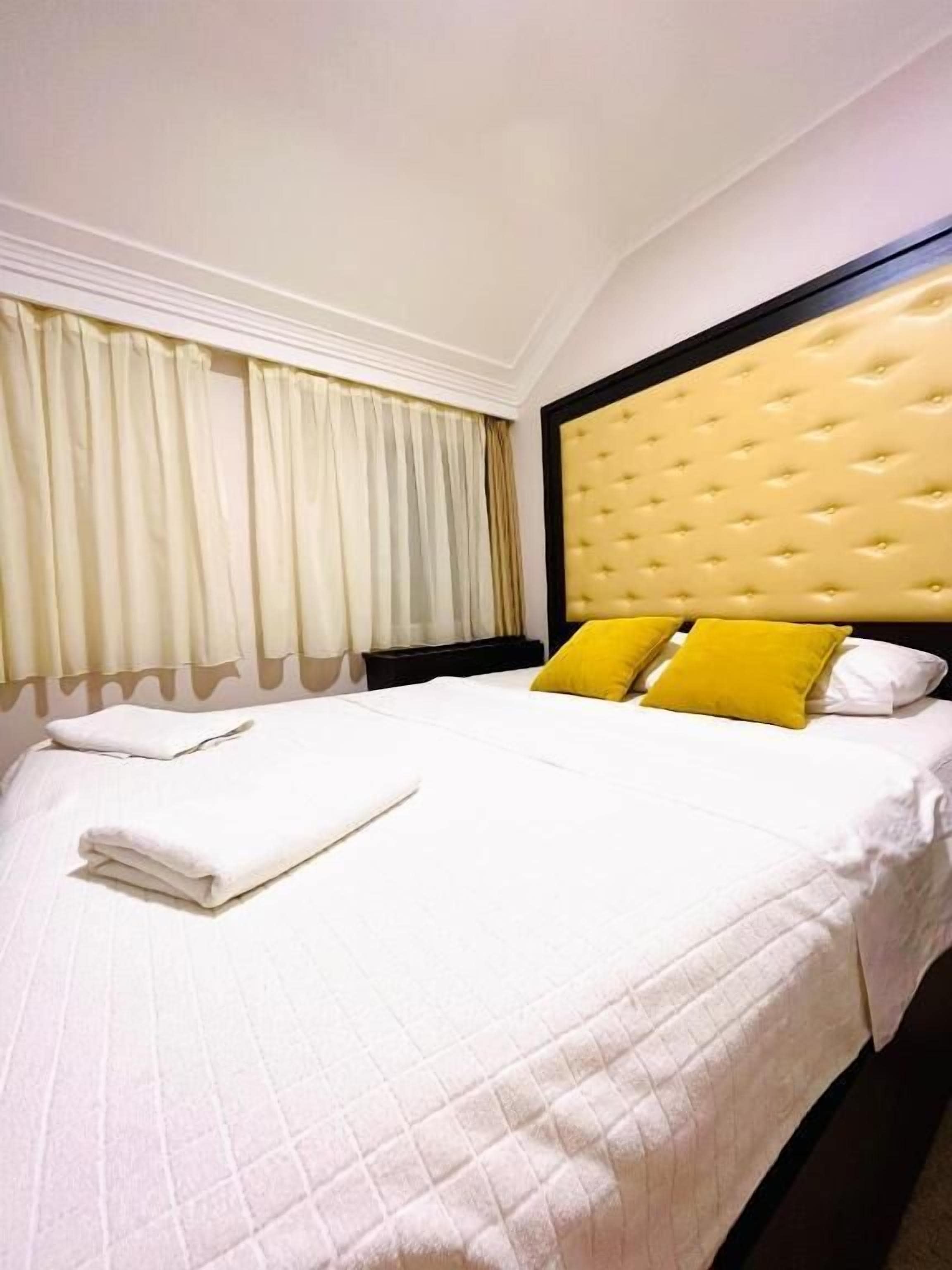 Una habitación de hotel con cama, cortinas y cabecero.