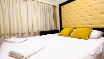 Una habitación de hotel con cama, cortinas y cabecero.