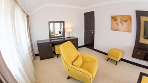A hotel room with a large window, a desk with a lamp, a chair, a small stool, and a wardrobe. - Swiss Holiday Hotel by Kundakcı Group (Rafajlovici)