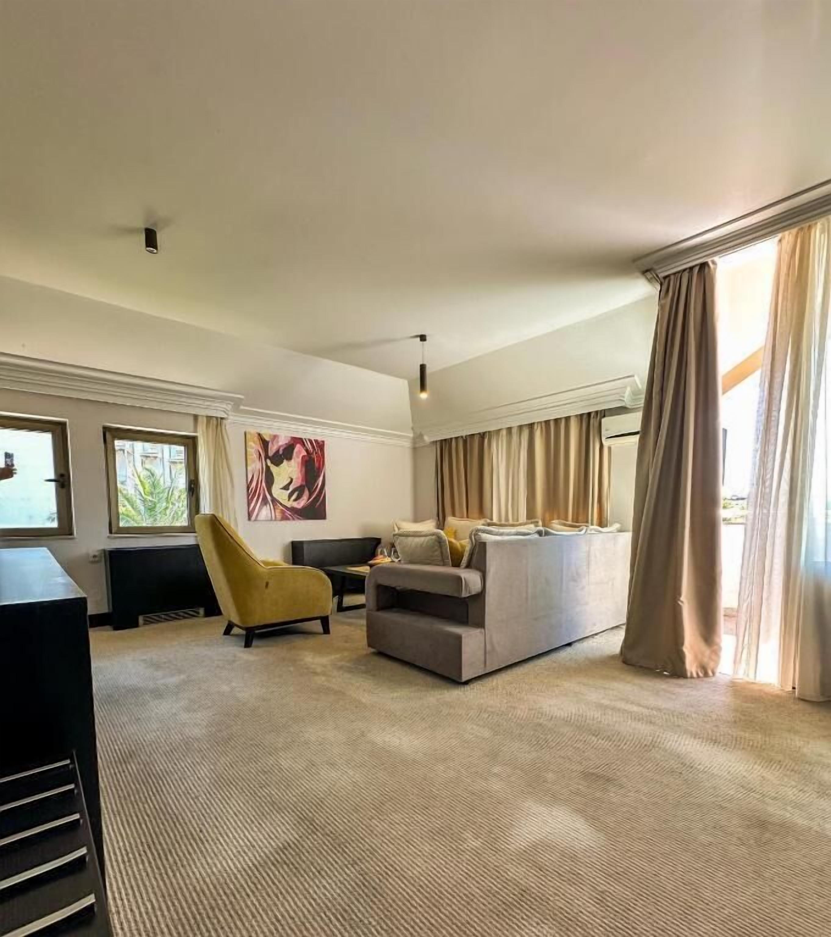 Un salón amplio con un conjunto de sofás, un sillón amarillo y un televisor de pantalla plana.