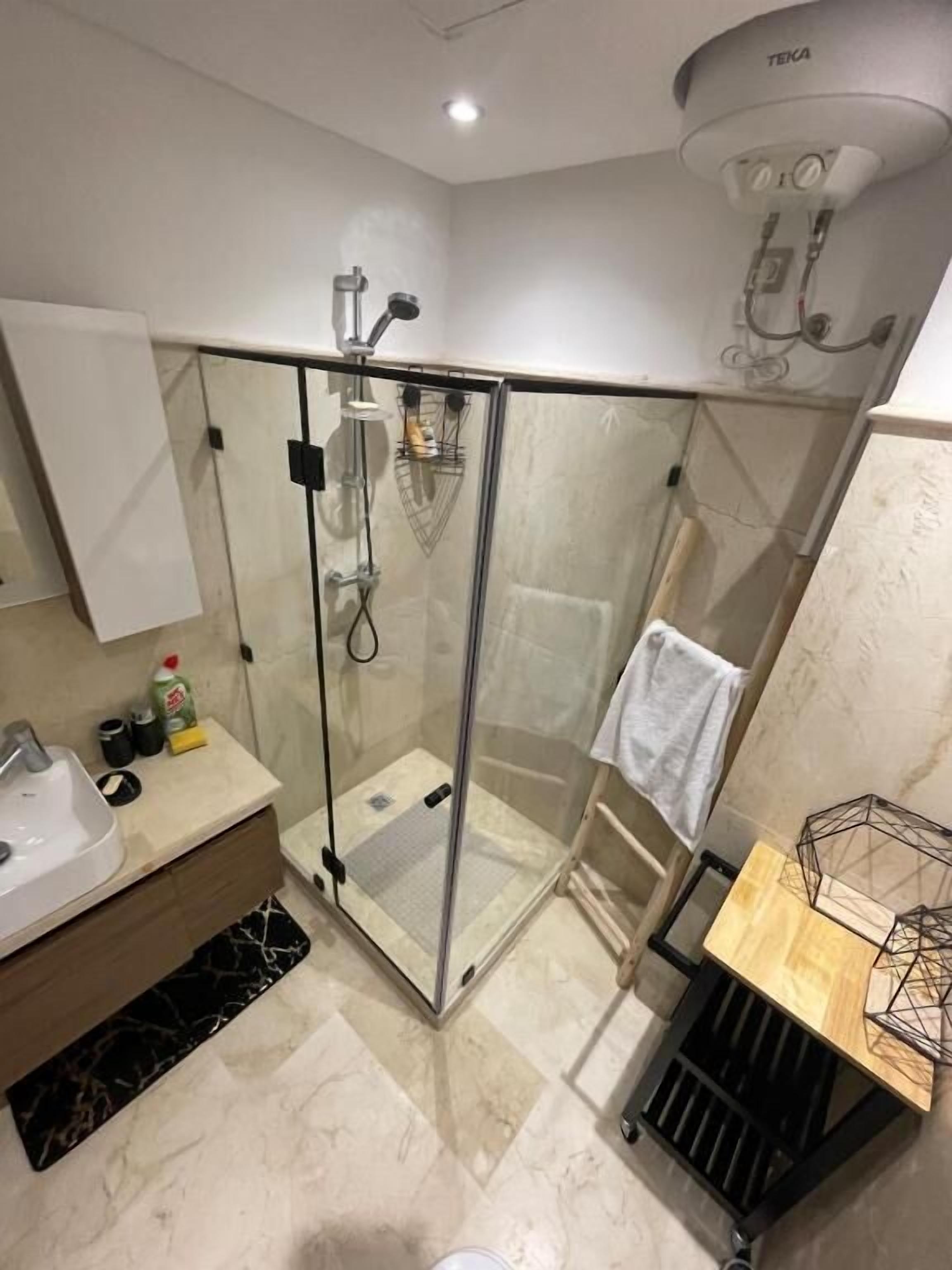 A modern bathroom with a glass-enclosed shower, a sink, and a towel rack.