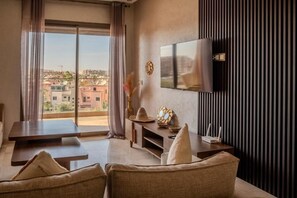 A modern living room with a sofa, a coffee table, and a flat-screen TV mounted on the wall.