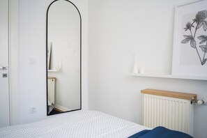 A bedroom with a bed, a mirror, a radiator, and a wall-mounted shelf with a plant illustration. - Stylish apartment with a separate bedroom near Taksim with AC (Istanbul)