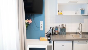 A modern kitchen with a flat-screen TV mounted on the wall, a coffee machine, and a sink with a stainless steel faucet. - Stylish apartment with a separate bedroom near Taksim with AC (Istanbul)