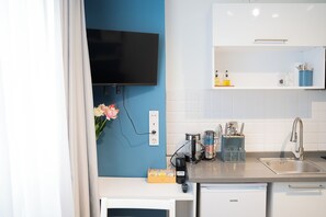 A modern kitchen with a flat-screen TV mounted on the wall, a coffee machine, and a sink with a stainless steel faucet. - Stylish apartment with a separate bedroom near Taksim with AC (Istanbul)