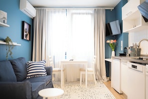 A compact living space with a sofa, a dining table, and a kitchen area. - Stylish apartment with a separate bedroom near Taksim with AC (Istanbul)