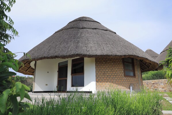 A thatched-roof house with a brick exterior, two visible windows, and a door.