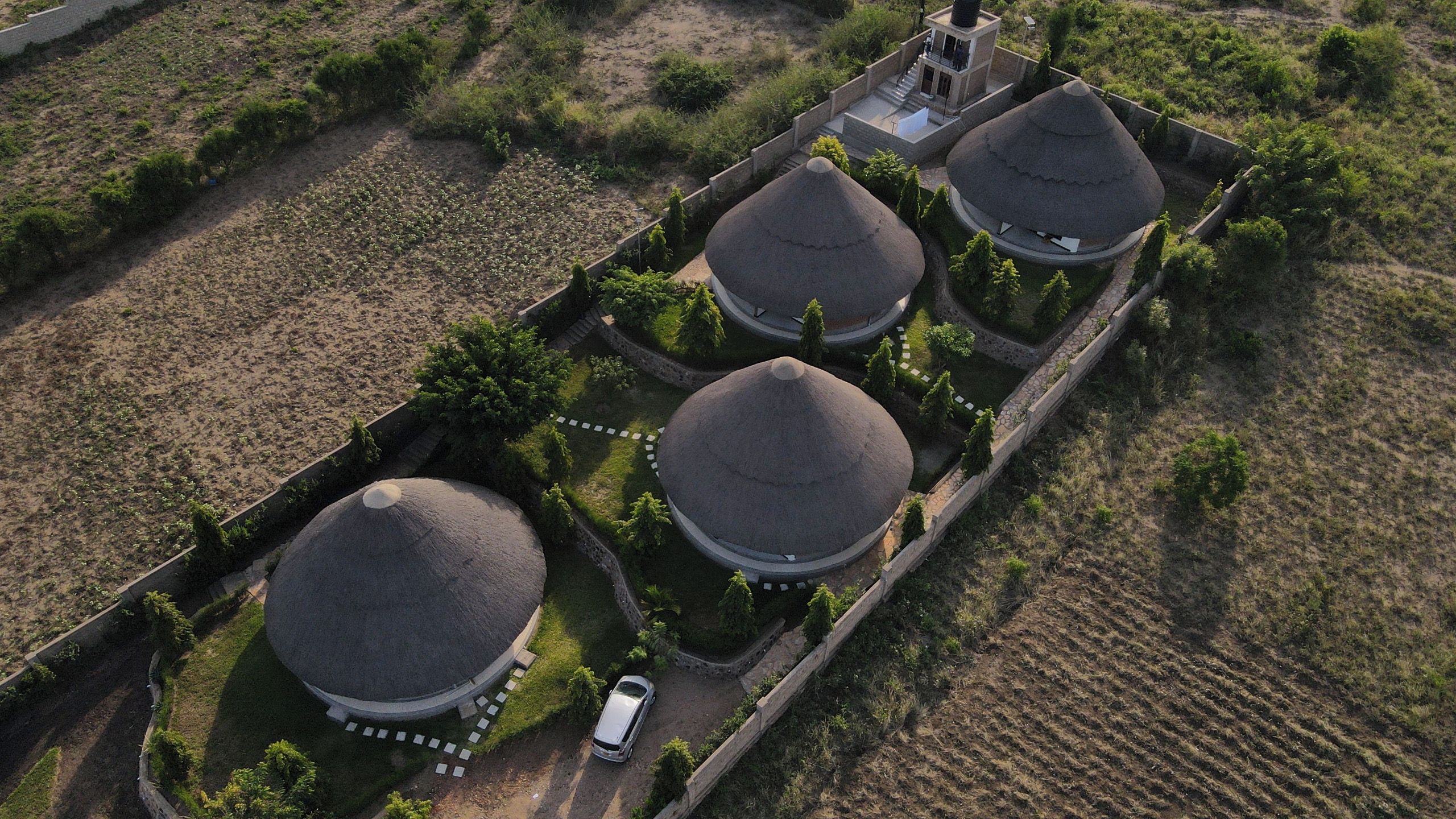 A large estate with three dome-shaped buildings, surrounded by a stone wall and a garden.