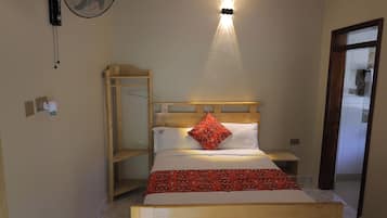 Quarto com cama, cabeceira de madeira, mesa de cabeceira, ventoinha pendurada e luminária.