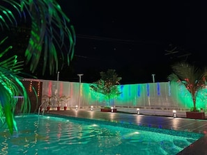Ein Pool mit Wasserspiel und einer Zierleiste mit bunten Lichtern.