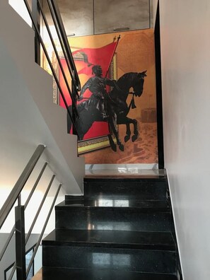 Eine Treppe mit schwarzem Geländer und einem Wandgemälde, das eine Person auf einem Pferd zeigt.